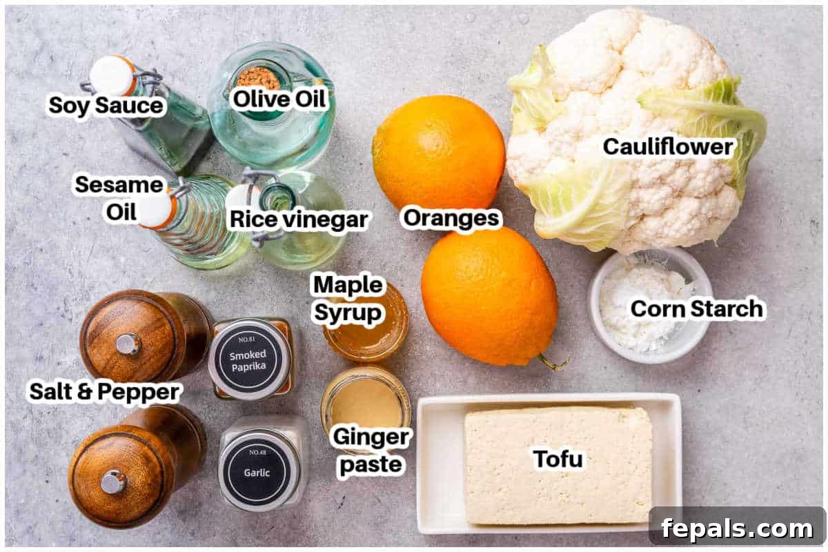 Crispy Orange Tofu 3 Various ingredients for crispy orange tofu laid out on a table, including cauliflower, tofu, cornstarch, oils, sauces, and spices.