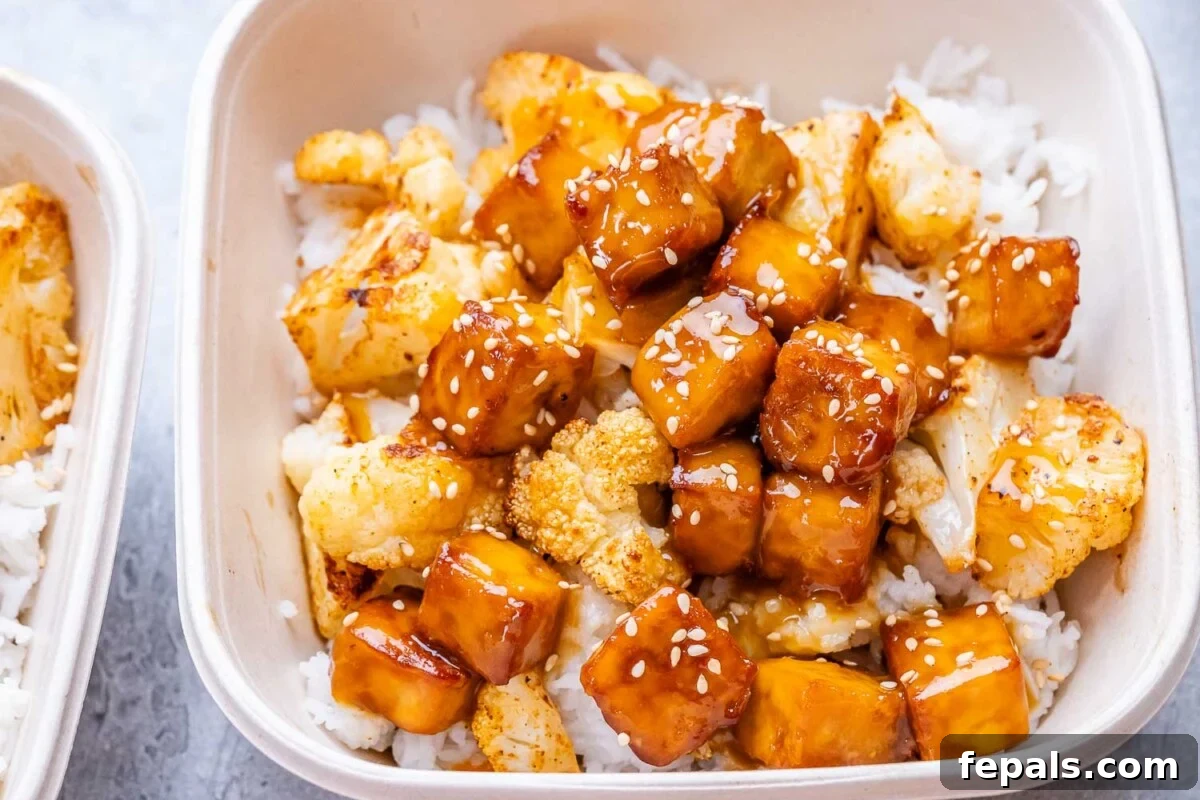 Crispy Orange Tofu 6 A bowl filled with sticky orange tofu and roasted cauliflower over rice.