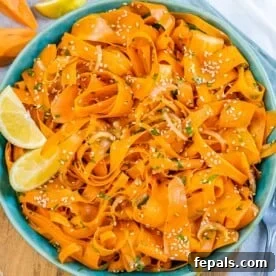 Sliced carrot salad in a round blue bowl.
