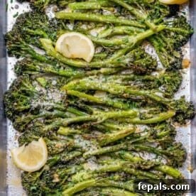 top view of roasted broccolini on a pan with lemon wedges