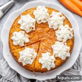 round carrot cake with slice cut off topped with creamy cheese frosting.