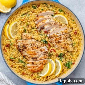 A beautiful blue skillet filled with creamy orzo, topped with perfectly sliced chicken breast and bright lemon wedges.