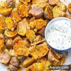 Crispy Parmesan roasted potatoes on a plate, perfectly seasoned and served with a creamy ranch dip for dipping.