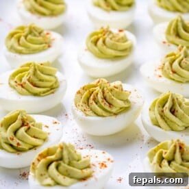 A sheet pan beautifully lined with vibrant green avocado deviled eggs, showcasing a healthy and colorful appetizer.
