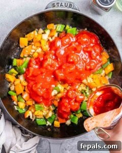 Adding tomatoes and seasonings to the sauce