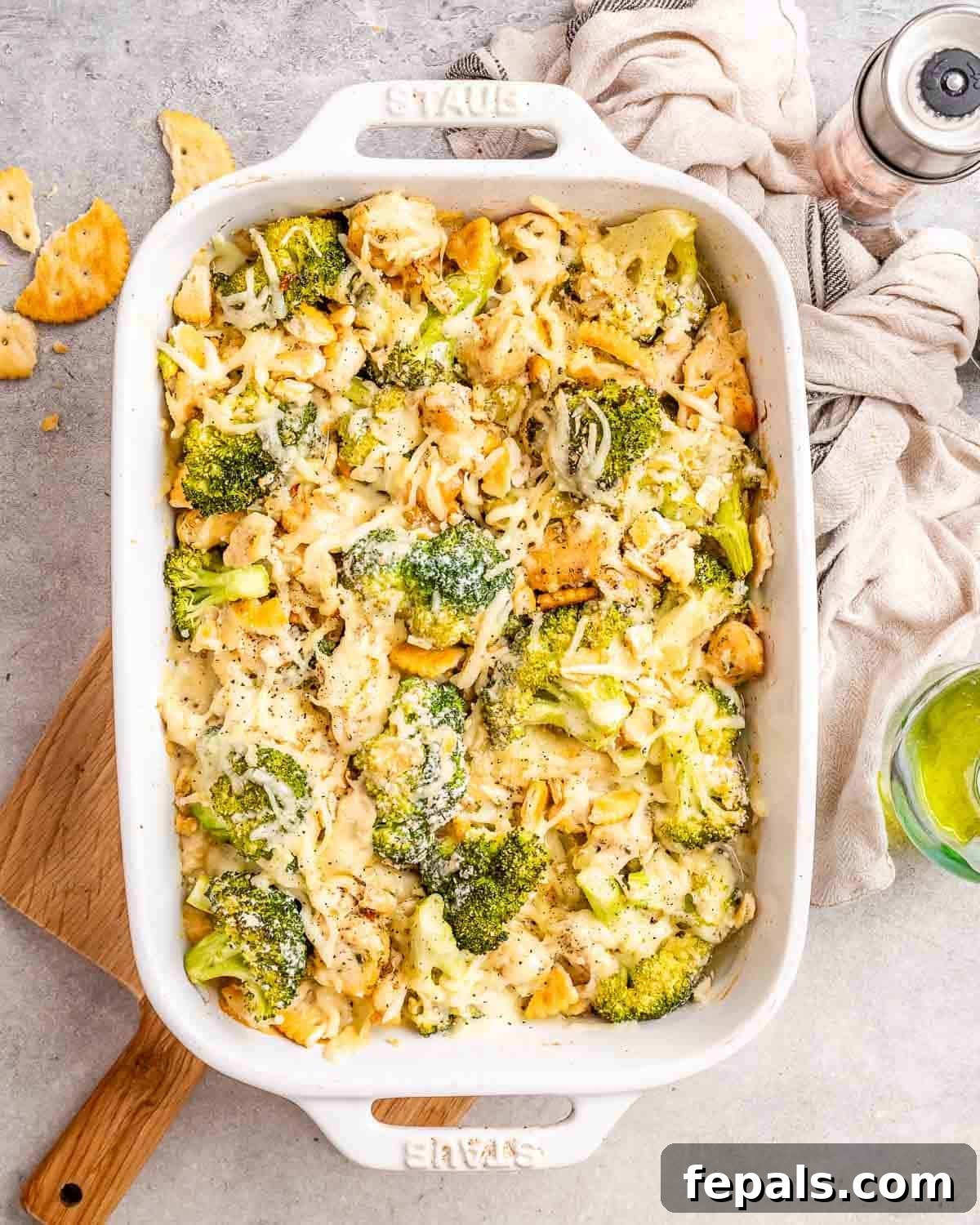 A casserole dish filled with golden-brown Chicken Divan, topped with melted shredded cheese and crunchy Ritz crackers, ready to be served.