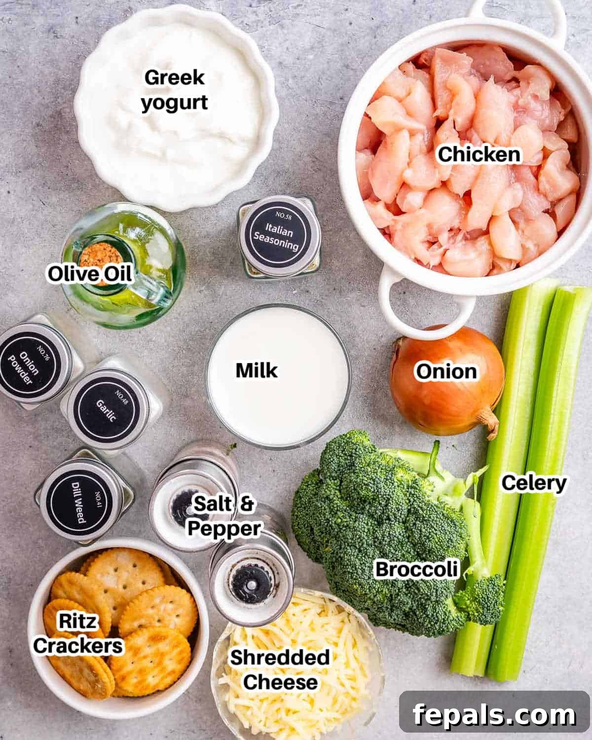 A collection of fresh ingredients laid out for preparing Chicken Divan, including chicken breast, broccoli, cheese, onion, celery, Greek yogurt, milk, and various seasonings.