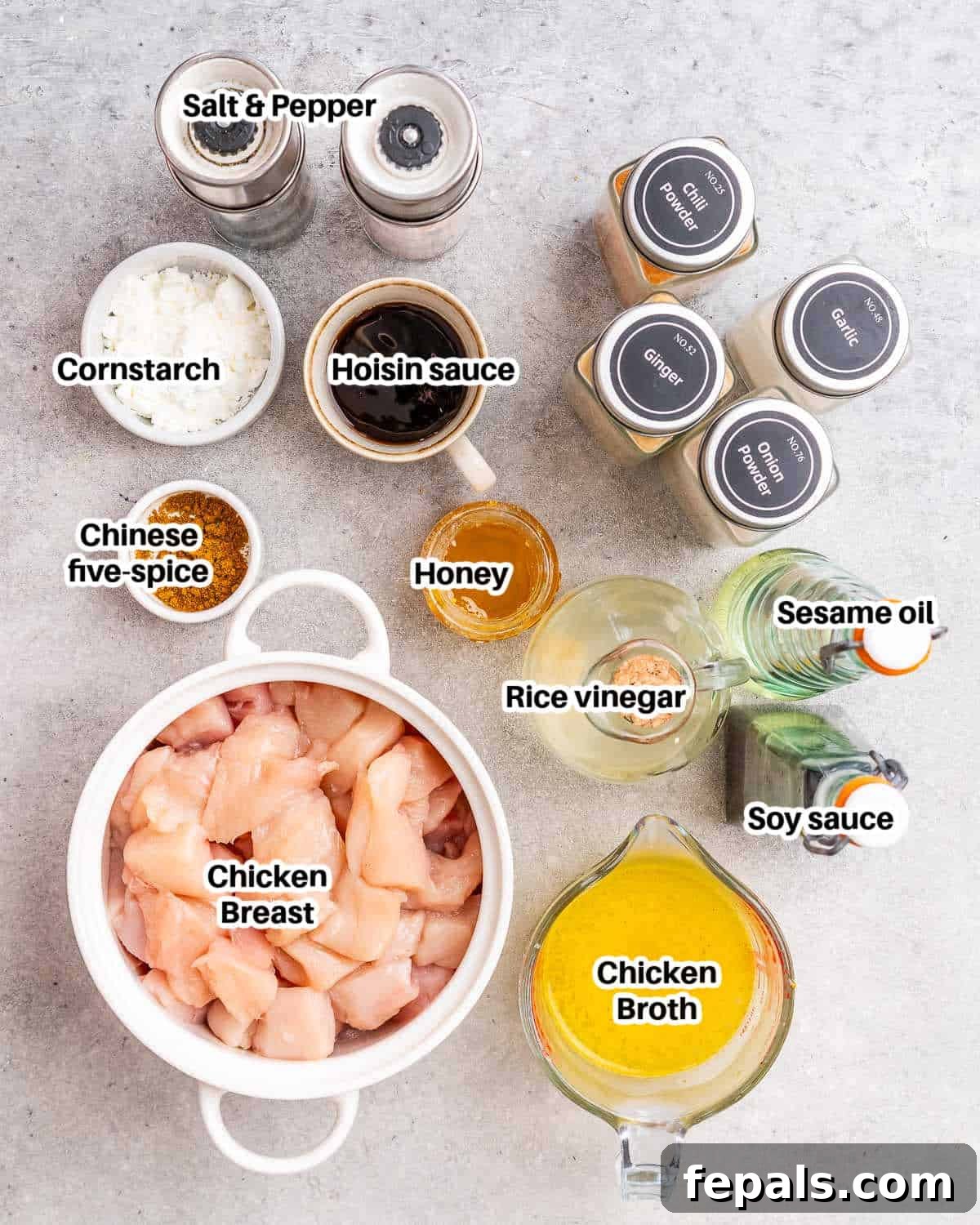 A collection of fresh ingredients laid out on a white surface, including raw chicken breast, a bowl of hoisin sauce, soy sauce, honey, rice vinegar, cornstarch, sesame oil, and various spices, ready to make hoisin chicken.