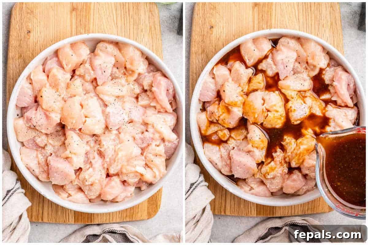 Raw chicken cubes mixed with cornstarch, sesame oil, and seasonings in a white bowl, ready for marinating.