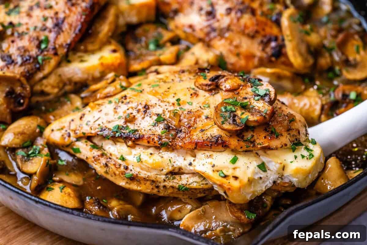 A hand reaching into a skillet with tongs to grab a piece of cooked stuffed chicken from the mushroom sauce.