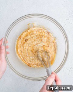 whisking yogurt, mashed banana, sugar, butter, and egg in a bowl.