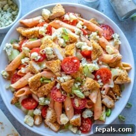A top-down view of Buffalo Chicken Pasta Salad, featuring golden pasta mixed with crunchy chicken pieces and vibrant vegetables, all coated in a spicy buffalo sauce.