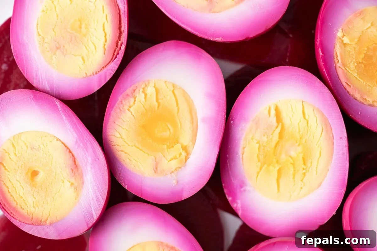 Ruby Red Pickled Eggs 9 Close up of halved beet picked eggs on a plate, showcasing the vibrant magenta color and perfectly set yolks.