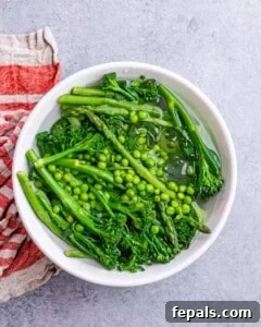 Blanched veggies in a white bowl filled with water.