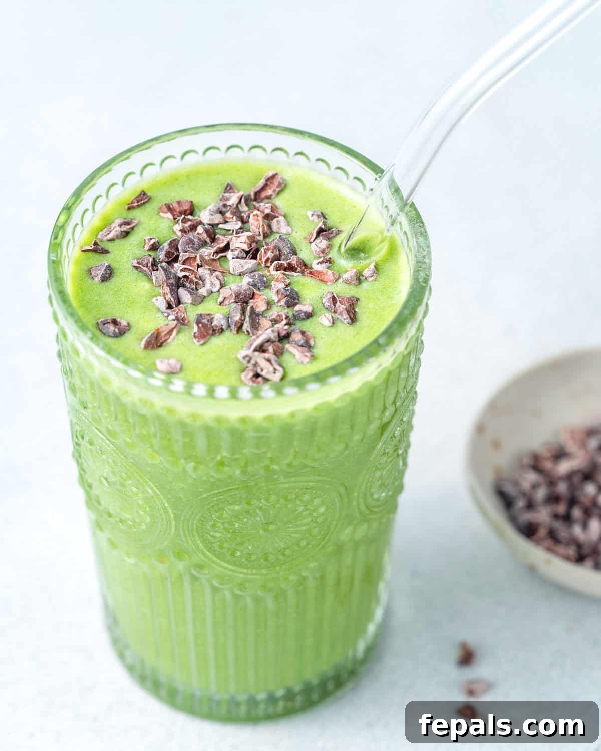 A vibrant green Shamrock Protein Shake, creamy and topped with dark cocoa nibs, inviting a healthy and delicious experience.