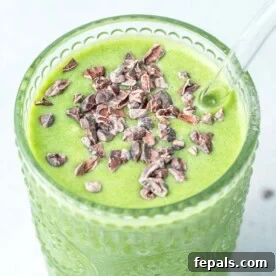 A cup full of a vibrant green shamrock shake, topped with rich cocoa nibs, perfect for a healthy and festive treat.