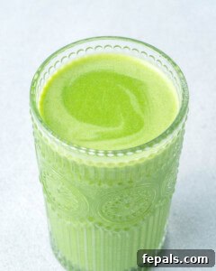 Green shamrock smoothie poured into a glass.