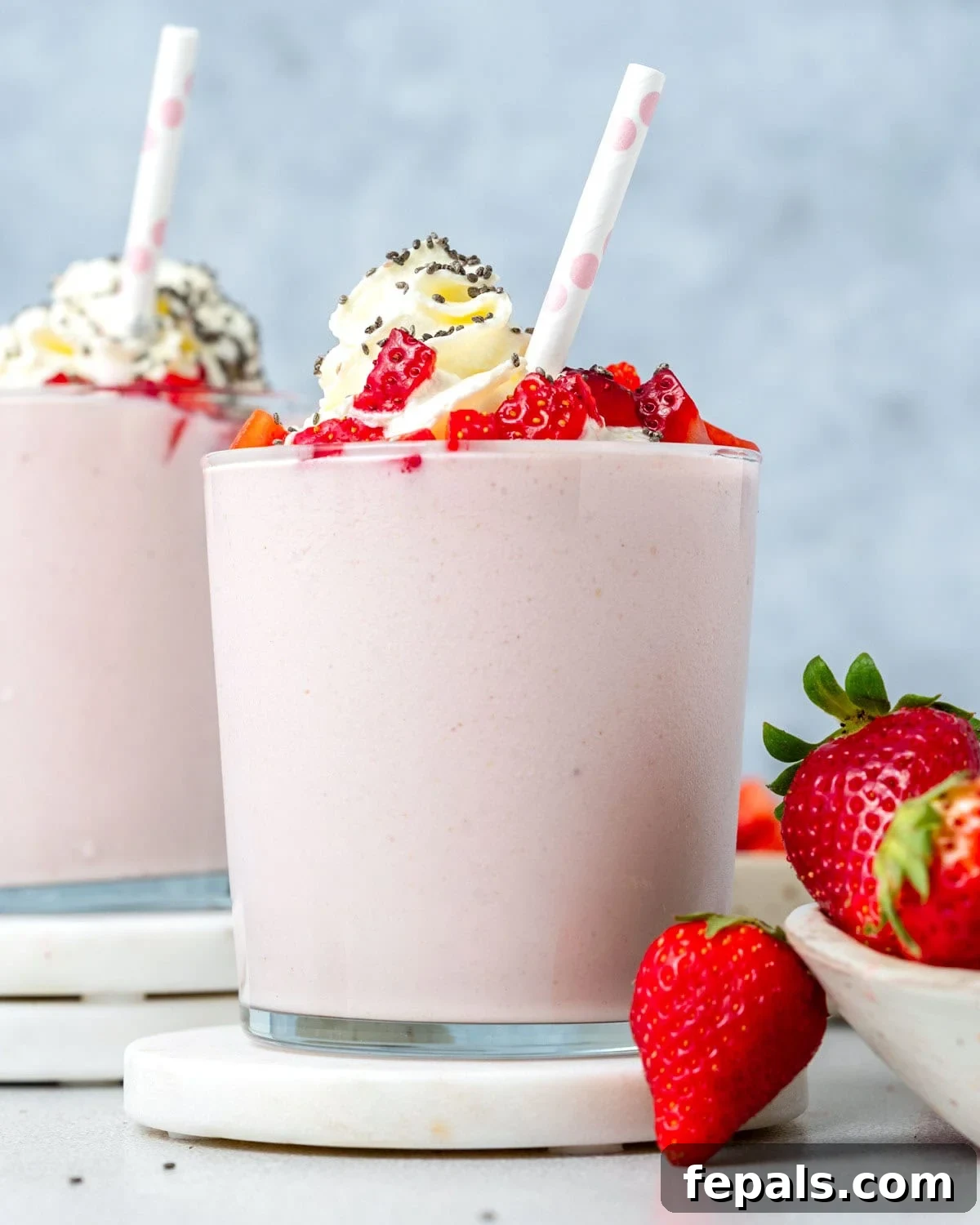 A vibrant strawberry cottage cheese smoothie, garnished with a dollop of whipped cream and fresh strawberry slices, perfectly chilled in a glass.