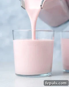 Pouring smoothie into a glass jar.