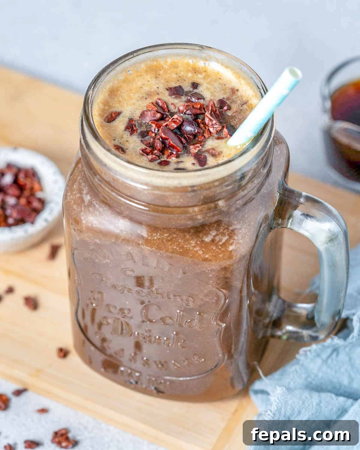 Brewed Protein Fuel 2 A mason jar filled with a creamy coffee protein shake, garnished with a straw and a few cocoa nibs.