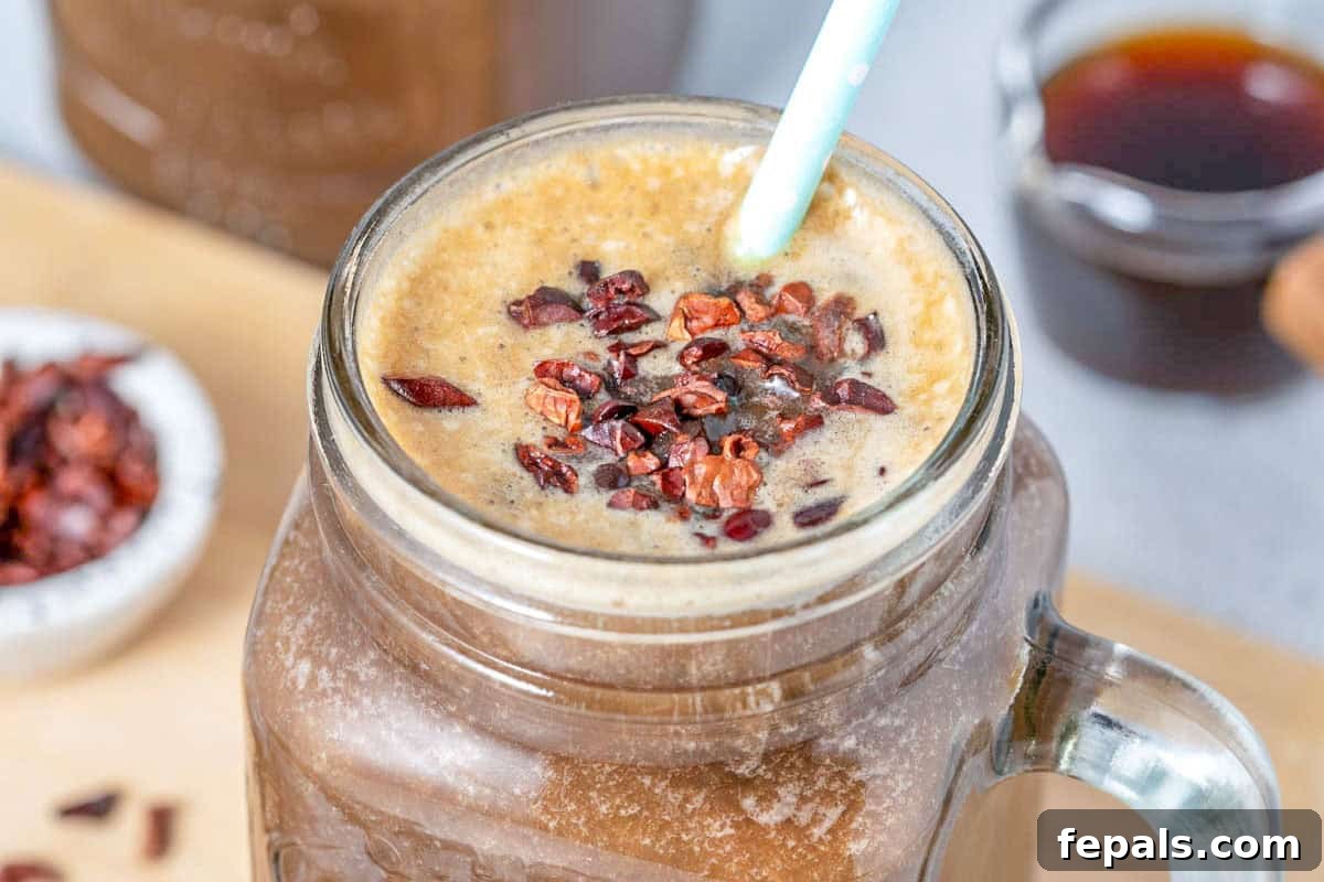 Brewed Protein Fuel 6 A mason jar filled with a coffee shake topped generously with crunchy cocoa nibs, with a straw for sipping.