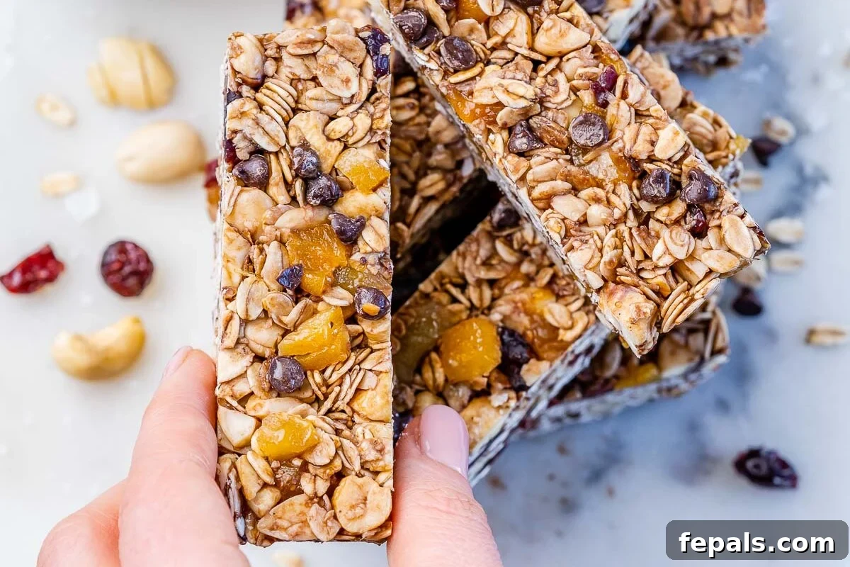 Hand holding up a healthy granola bar above a stack of granola bars.