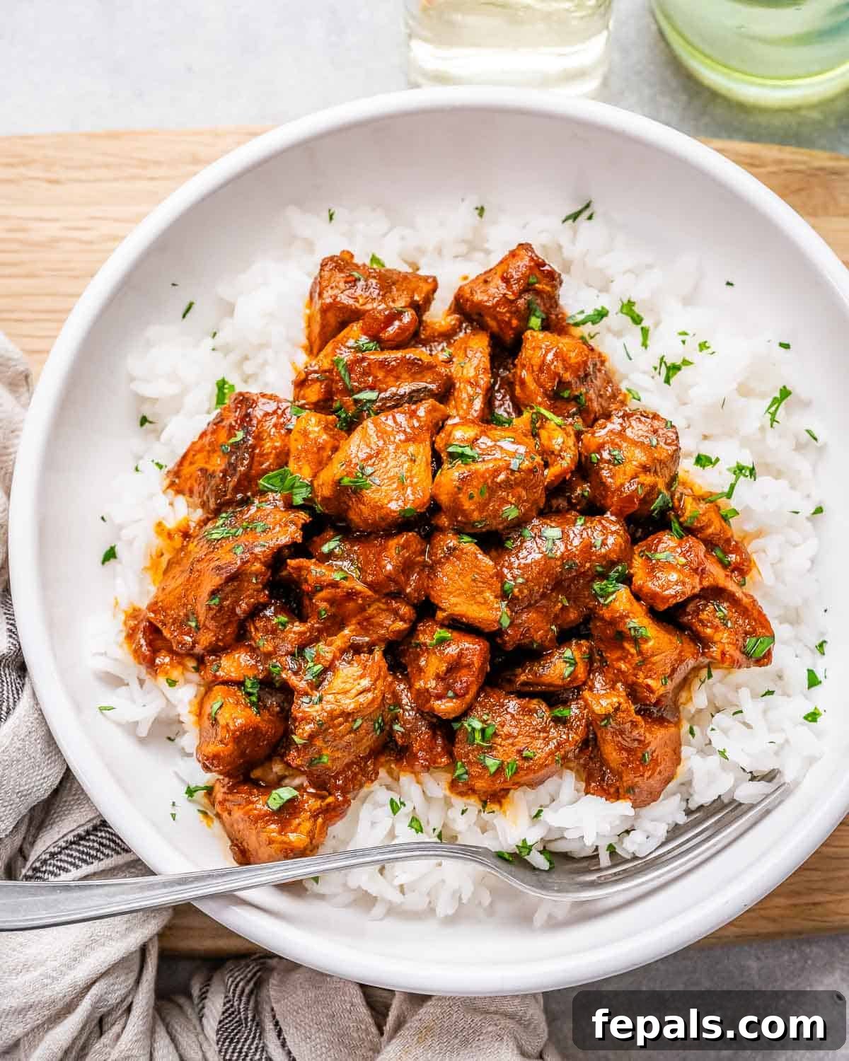 Fiery Goan Chicken Vindaloo 2 A white bowl of chicken vindaloo served alongside fluffy white rice, garnished with fresh cilantro.