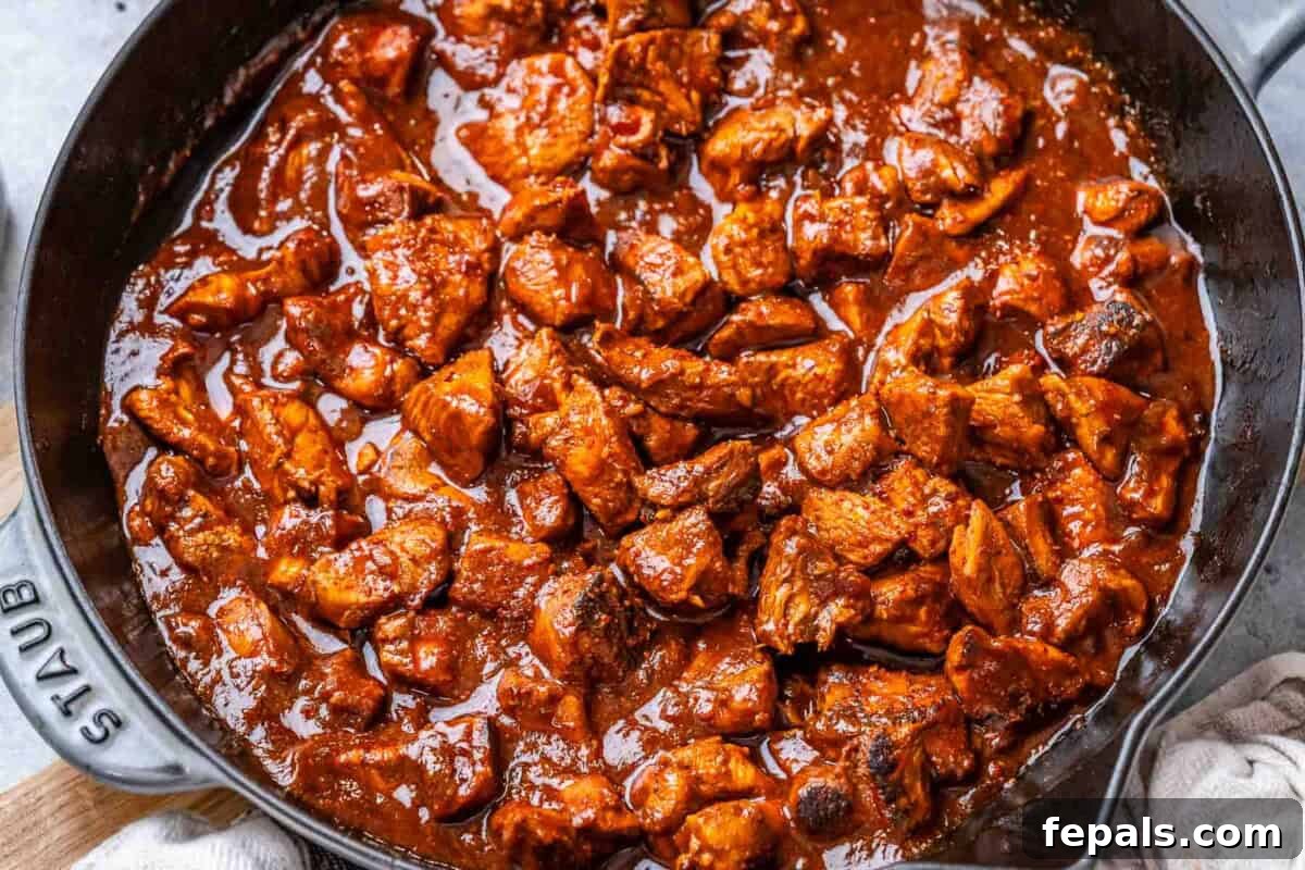 Fiery Goan Chicken Vindaloo 7 A black cast iron skillet filled with simmering chicken vindaloo, ready to be served.