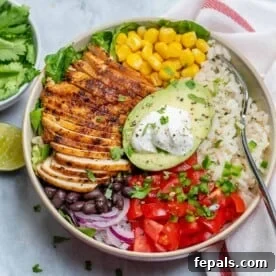 Effortless Cinco De Mayo Feast 7 top view of a burrito bowl with sliced grilled chicken, rice, black beans, corn, tomatoes, and half avocado in the middle