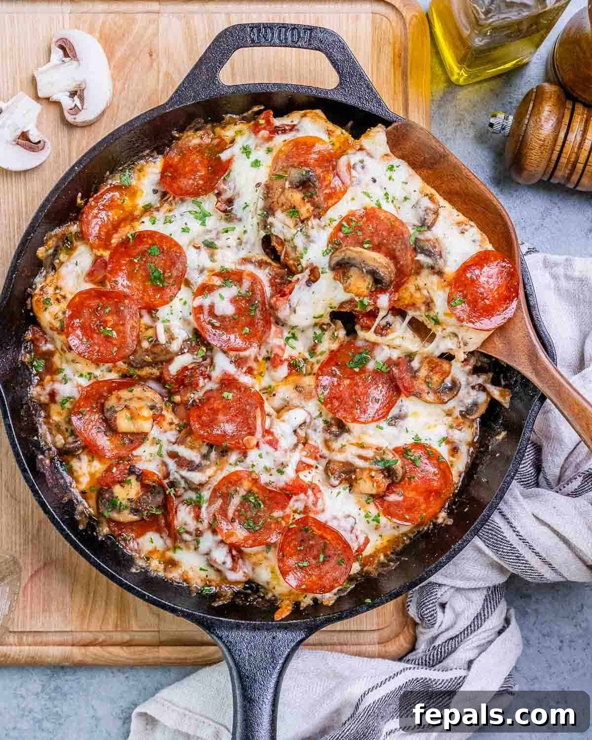 Homestyle Chicken Pizzaiola 7 Beautifully cooked Chicken Pizzaiola with melted mozzarella and pepperoni, presented in a cast iron skillet on a rustic wooden board.