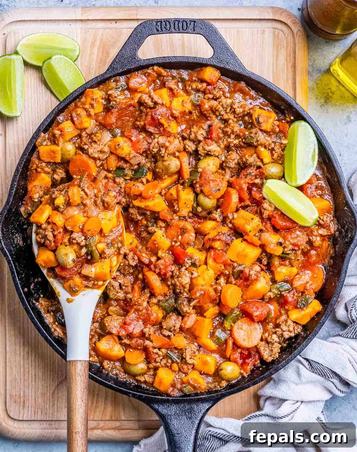 Hearty Mexican Picadillo 8 A black skillet filled with rich Mexican picadillo, garnished with fresh herbs, sitting on a rustic wooden board.
