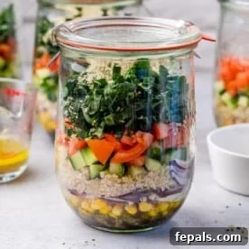 Side shot of a vibrant Italian kale salad layered in a mason jar, showcasing its fresh ingredients.