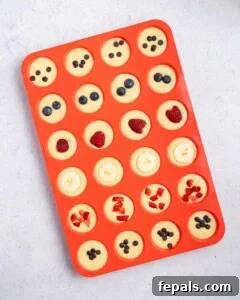 pancake batter in muffin tins topped with fruits.