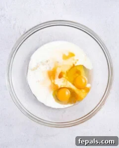 a bowl with eggs, oil, and milk.