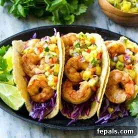 Three spicy shrimp tacos on a plate, garnished with fresh lime and shredded cabbage, offering a burst of flavor.