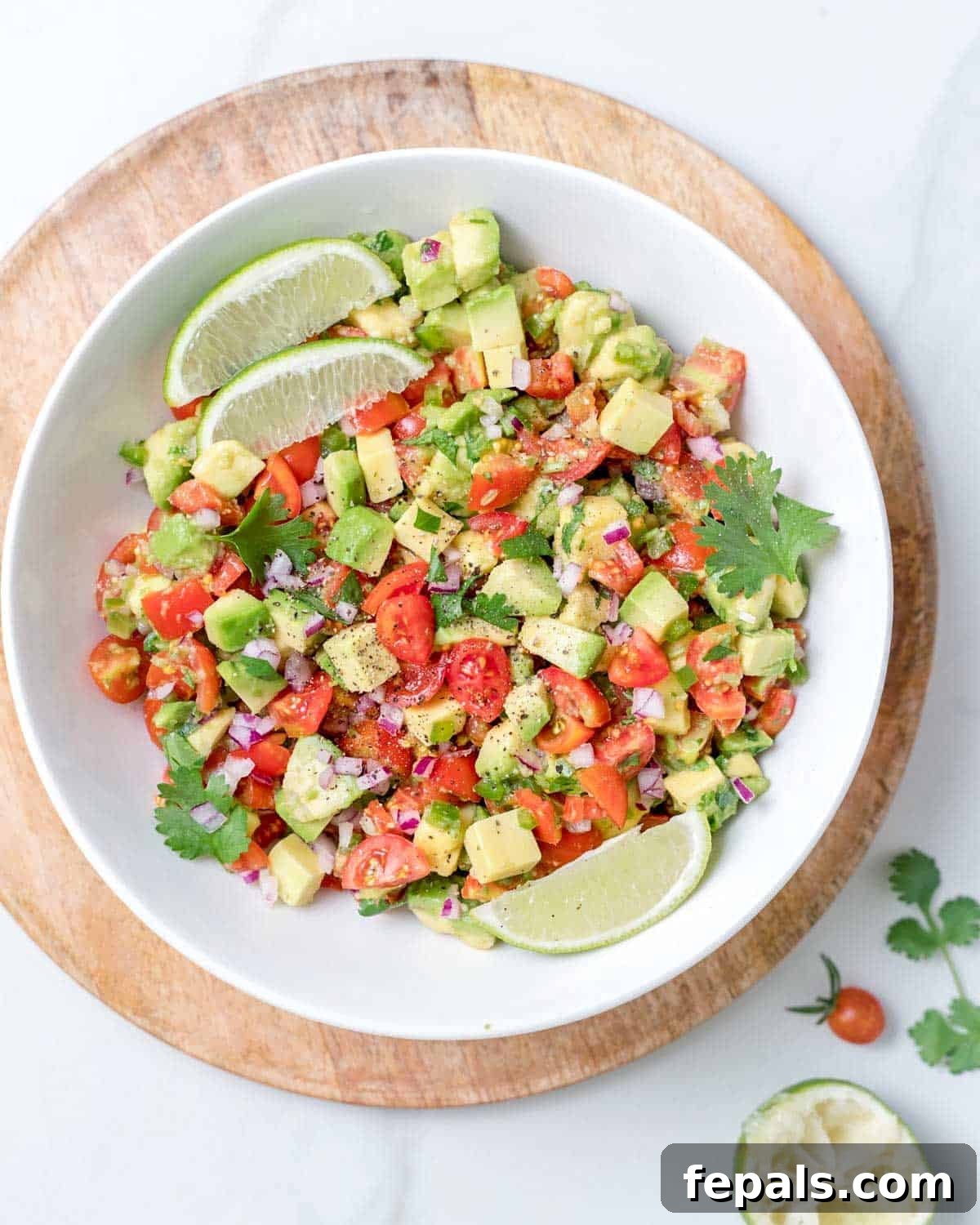 A beautifully presented bowl of avocado salsa topped with fresh lime wedges, ready to be served.