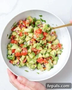 A spoon mixing the salsa ingredients in a bowl, demonstrating the combining process.