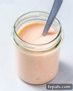 A jar with bang bang sauce with a spoon in the jar.