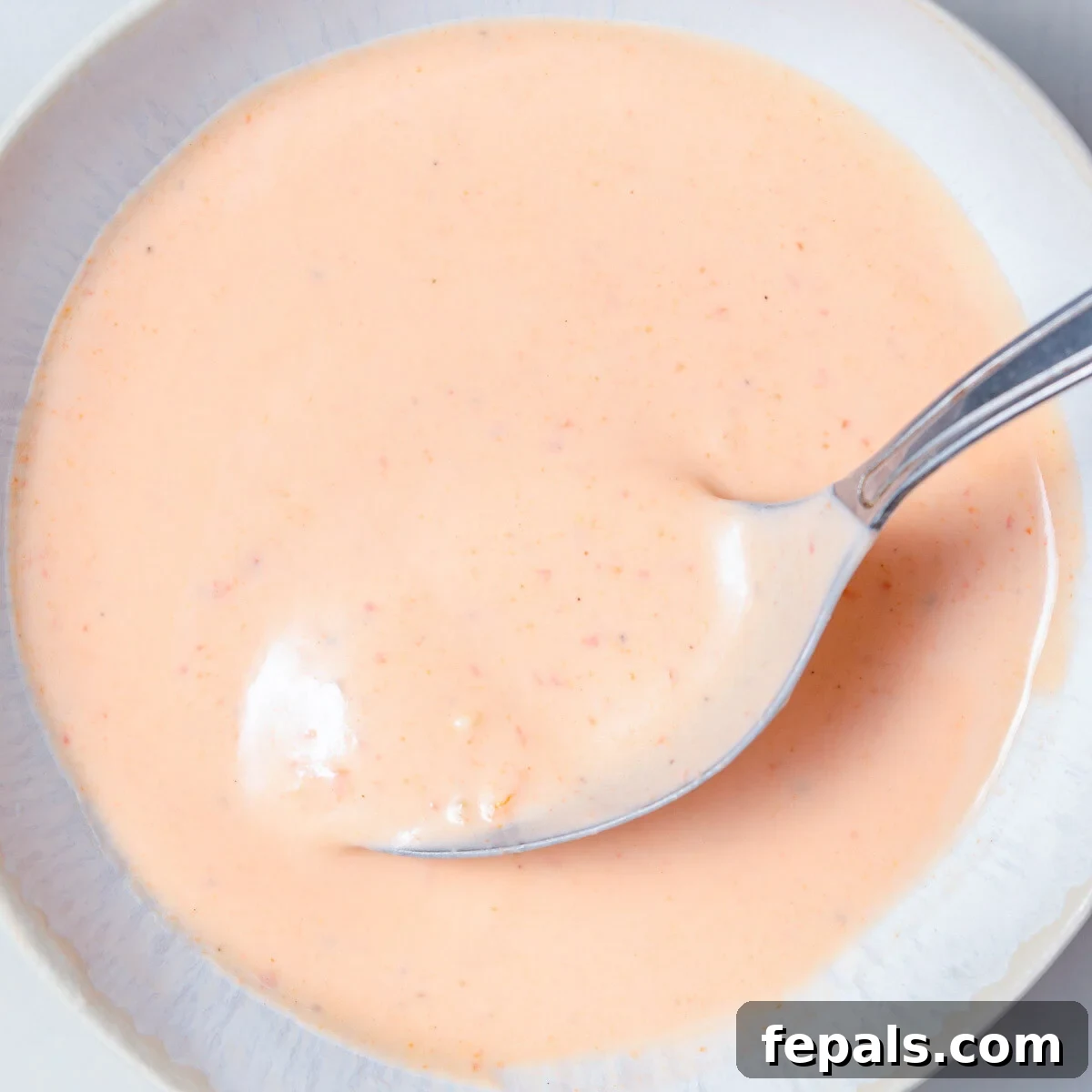 Irresistible Bang Bang Sauce 6 A serving bowl filled with creamy homemade Bang Bang sauce, with a small spoon resting in it.