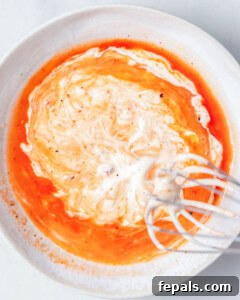 whisking Bang Bang sauce in a bowl.