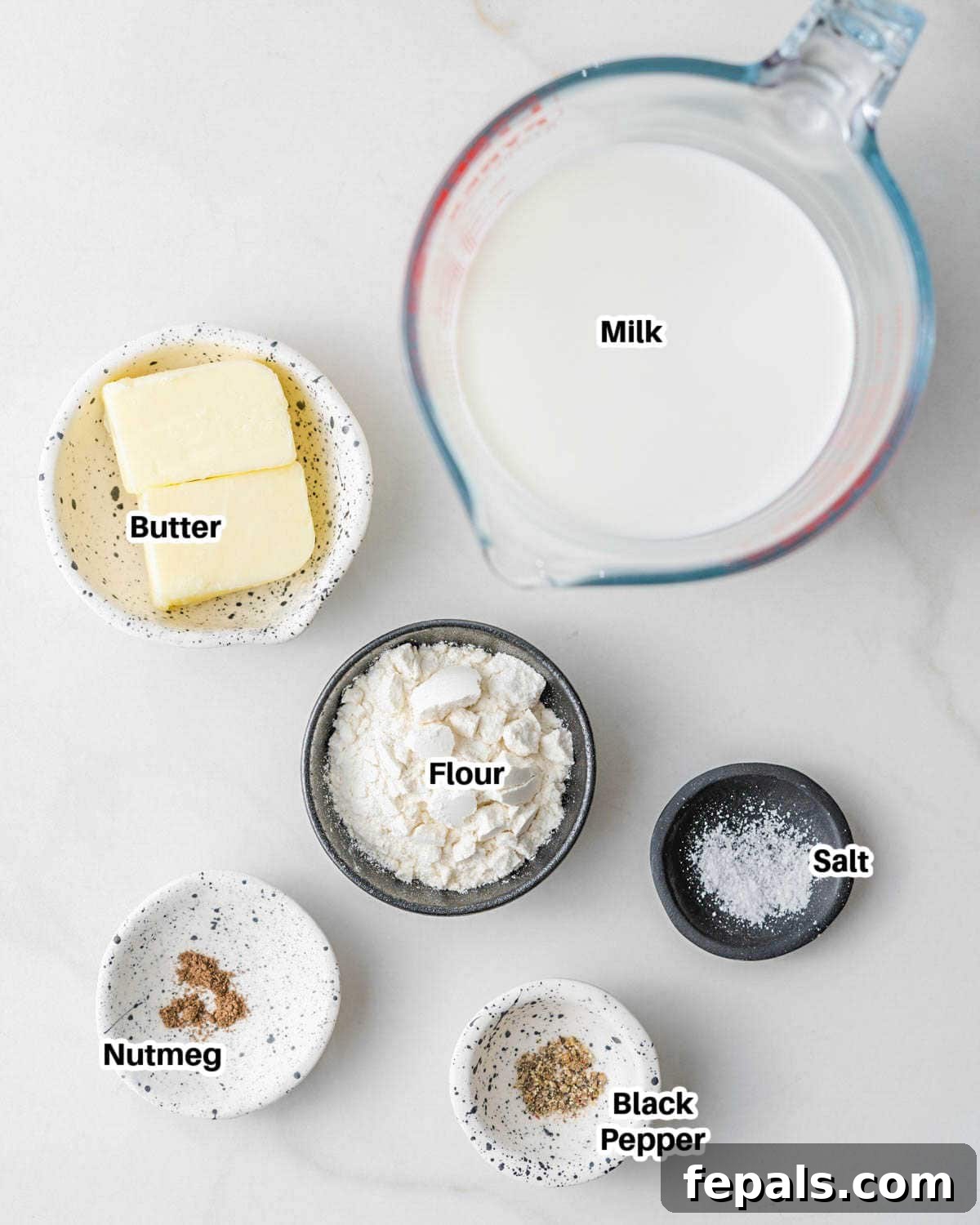 A selection of basic ingredients for Bechamel sauce, including butter, flour, and a bottle of milk, arranged neatly on a kitchen counter.