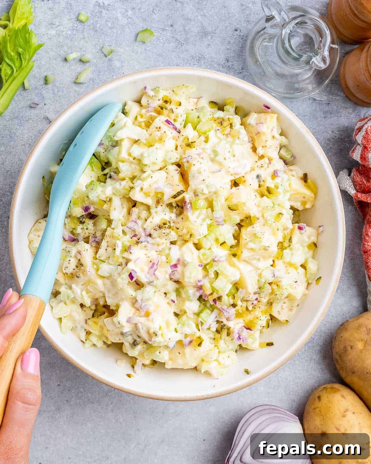 Overhead shot of Southern potato salad fully mixed and ready to serve, scooped with a teal serving spoon.
