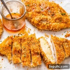 sliced crispy chicken cutlets topped with honey on a sheet pan.