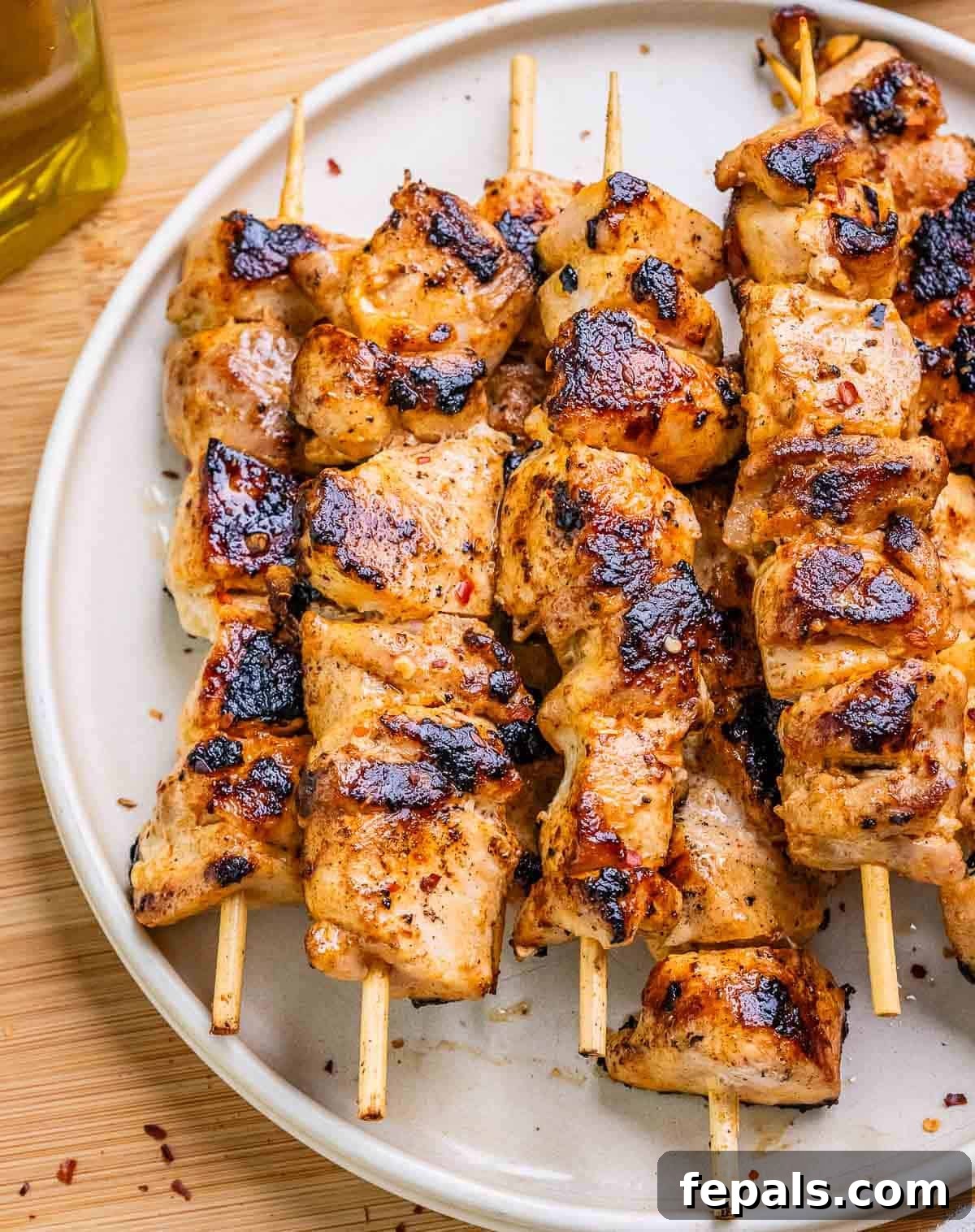 Firecracker Chicken Skewers 2 A plate of perfectly grilled Bang Bang Chicken Skewers, garnished with sesame seeds and fresh herbs.