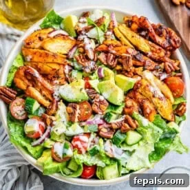 a round bowl of salad topped with sliced BBQ chicken thighs.