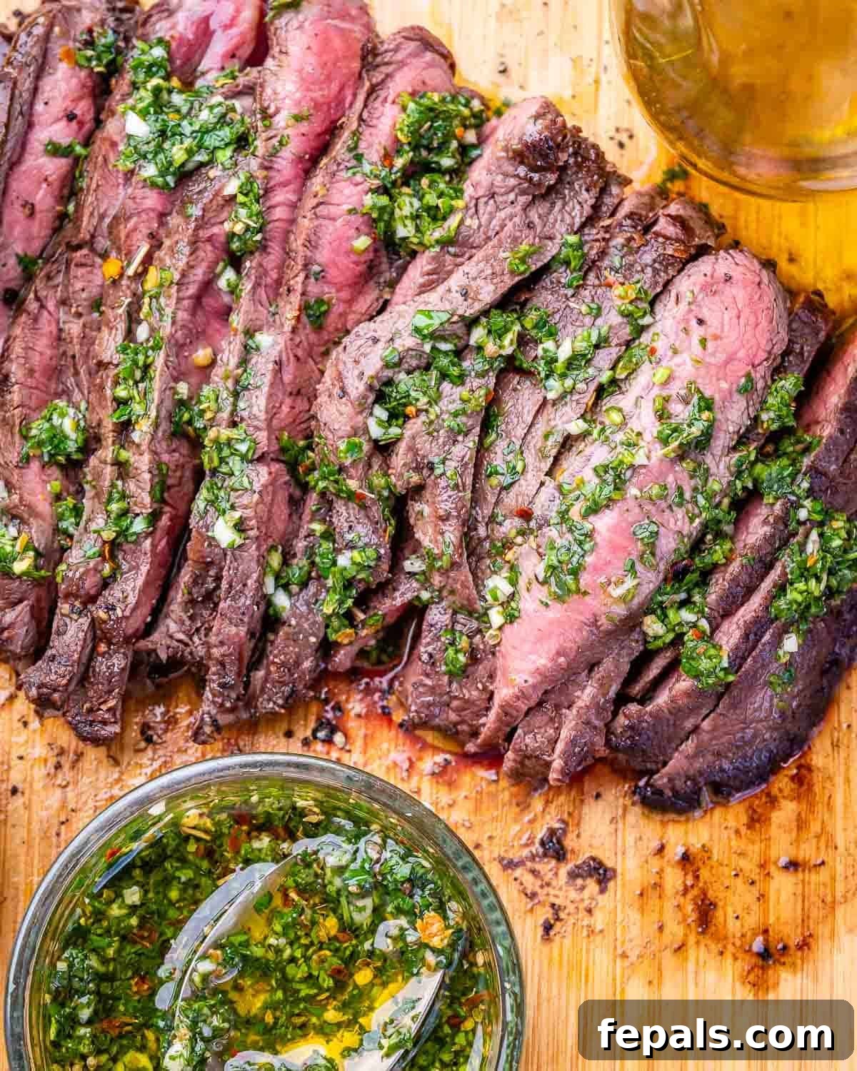 30-Minute Grilled Steak with Fresh Chimichurri Sauce 5 Sliced grilled steak on a wooden board with homemade chimichurri.