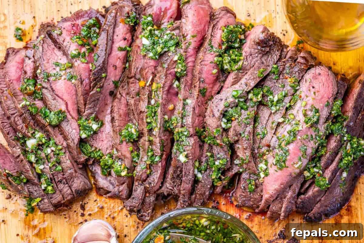 30-Minute Grilled Steak with Fresh Chimichurri Sauce 6 sliced steak on a cutting board topped with chimichurri sauce.