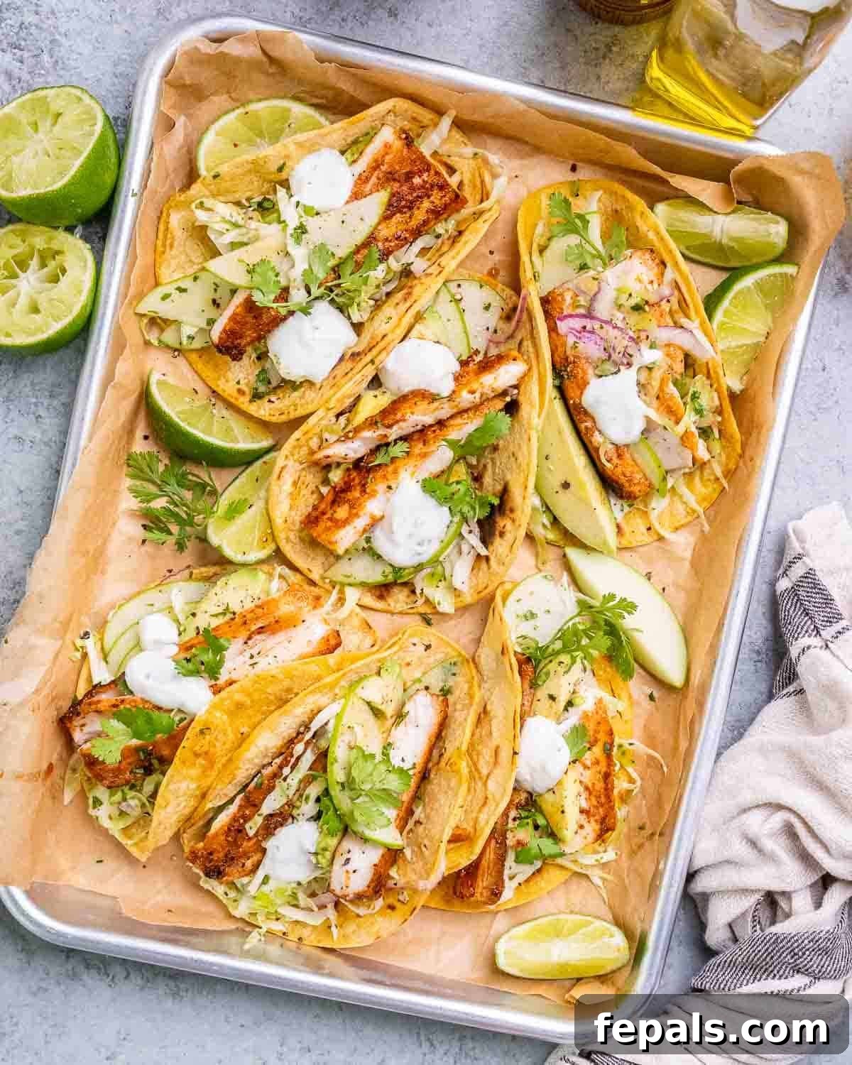 Crispy Mahi Mahi Tacos with Cilantro-Lime Crema 7 A tray of mahi mahi fish tacos with cabbage slaw and lime wedges.