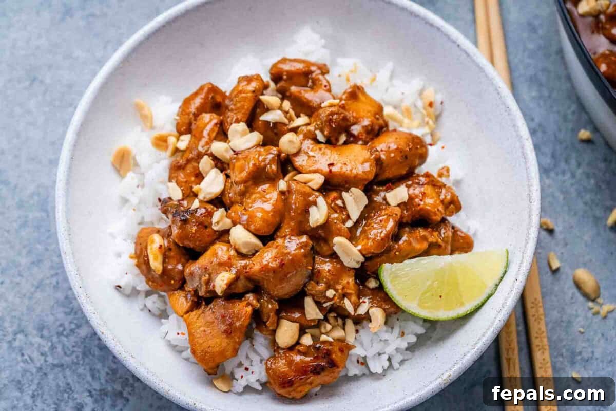 seared chicken in peanut butter sauce added over white rice in a bowl.