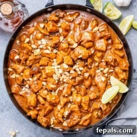 a large black skillet of chicken bites cooked in a peanut butter sauce.